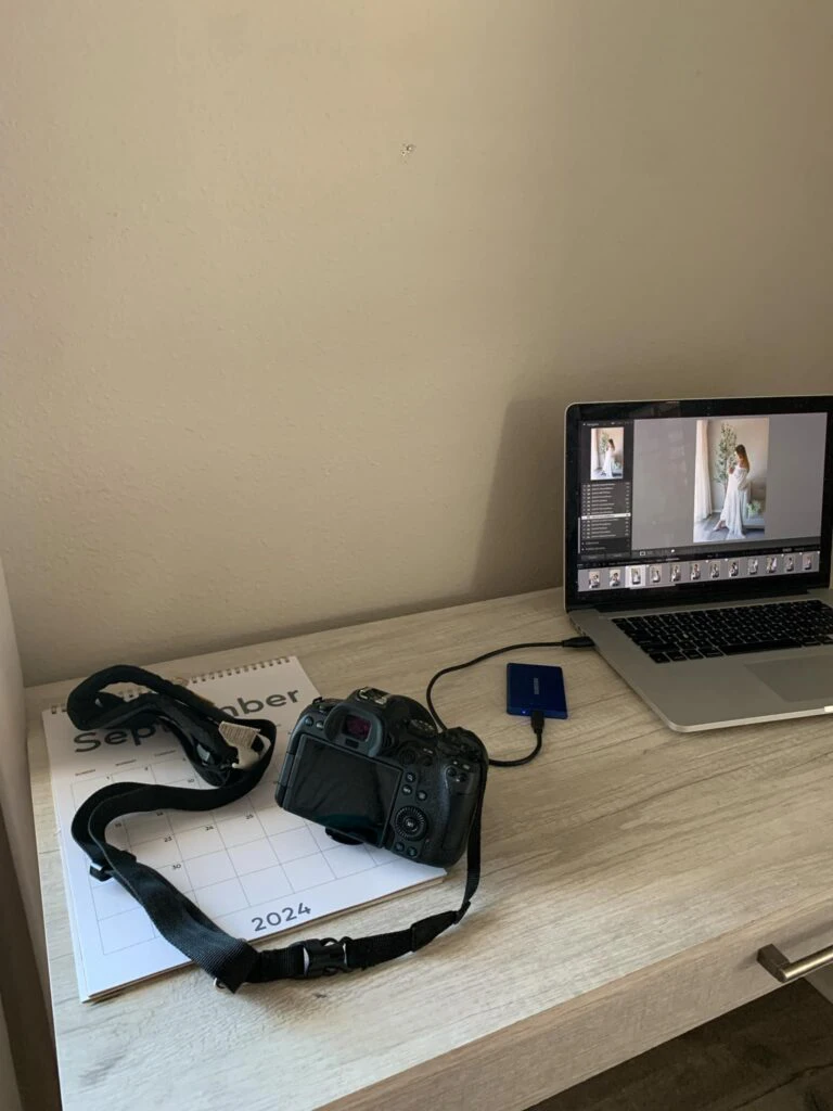 Photography workspace with a DSLR camera and laptop editing a bridal portrait.